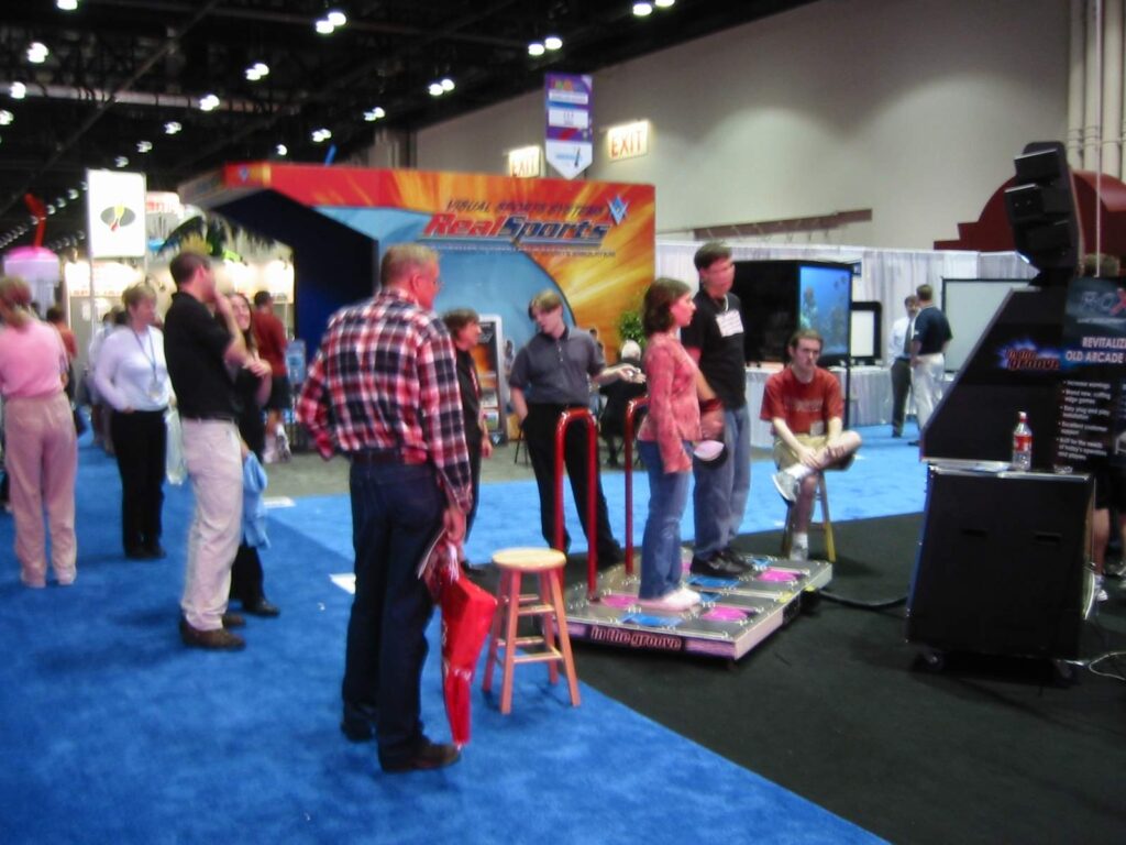 Families gather around a dance-game stage at a trade show