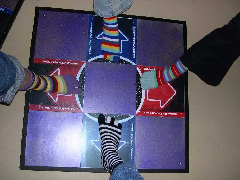 Four feet in colorful socks share one dance pad