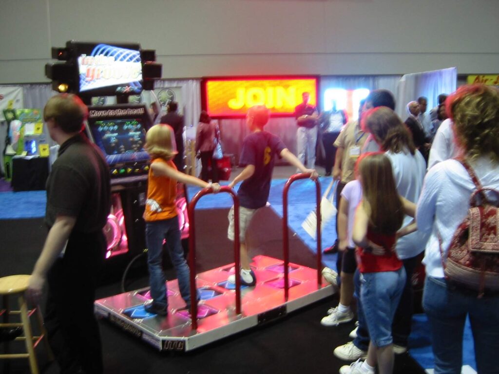 A girl dances on a dance-game stage while a crowd of kids watches